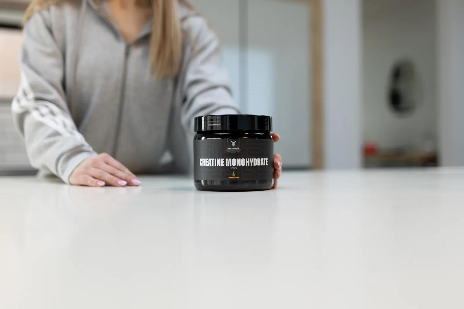 Woman placing a 500g jar of Inception Labs Creatine Monohydrate on a kitchen counter