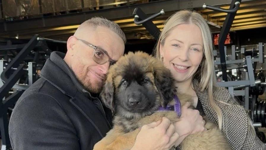 Inception Gym Christchurch founders Matt and Elise Walley holding Maple, their Leonberger puppy, on the training floor